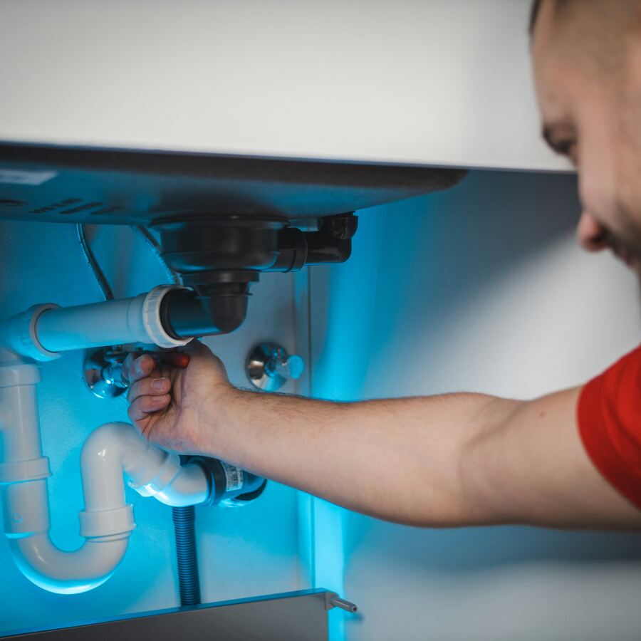 Plumber repairing pipes under a kitchen sink