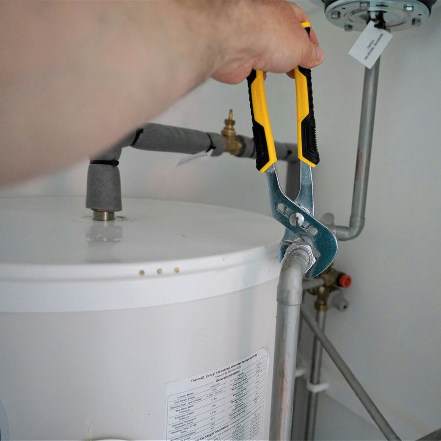 Plumber servicing a residential water heater tank